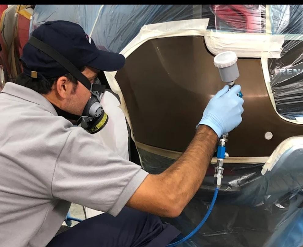 Profissional da SpeedRepair realizando pintura automotiva com mascaramento e equipamento adequado